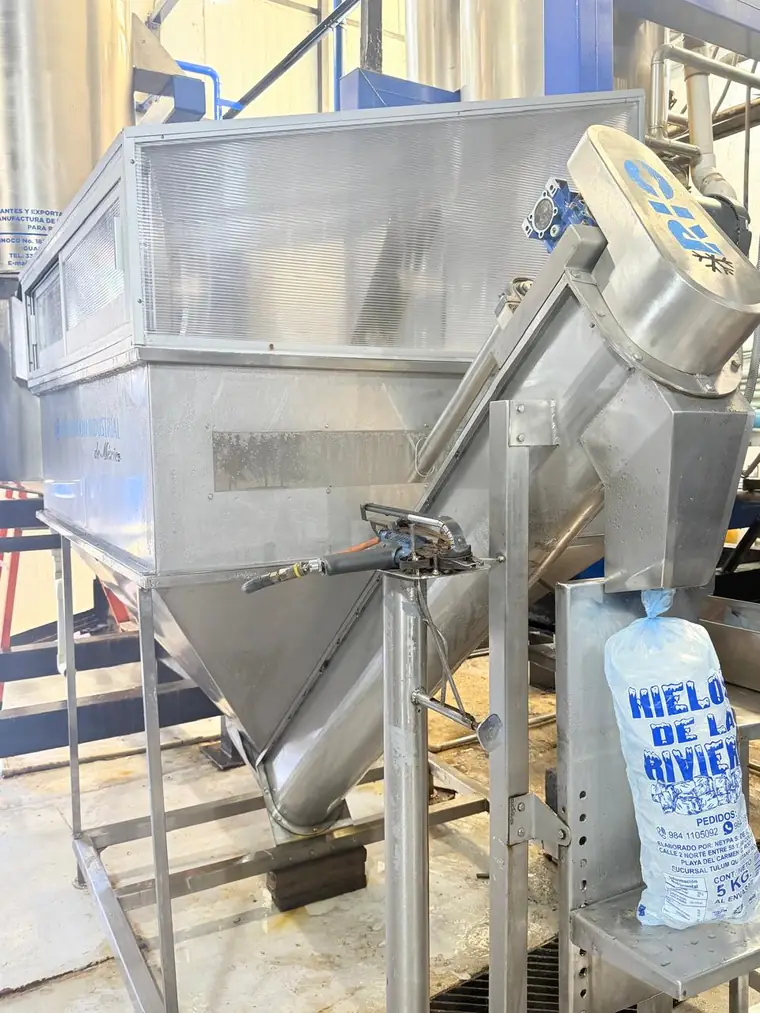 Tolva y ensacadora de acero inoxidable llenando una bolsa de 5 kg de Hielos de la Riviera.