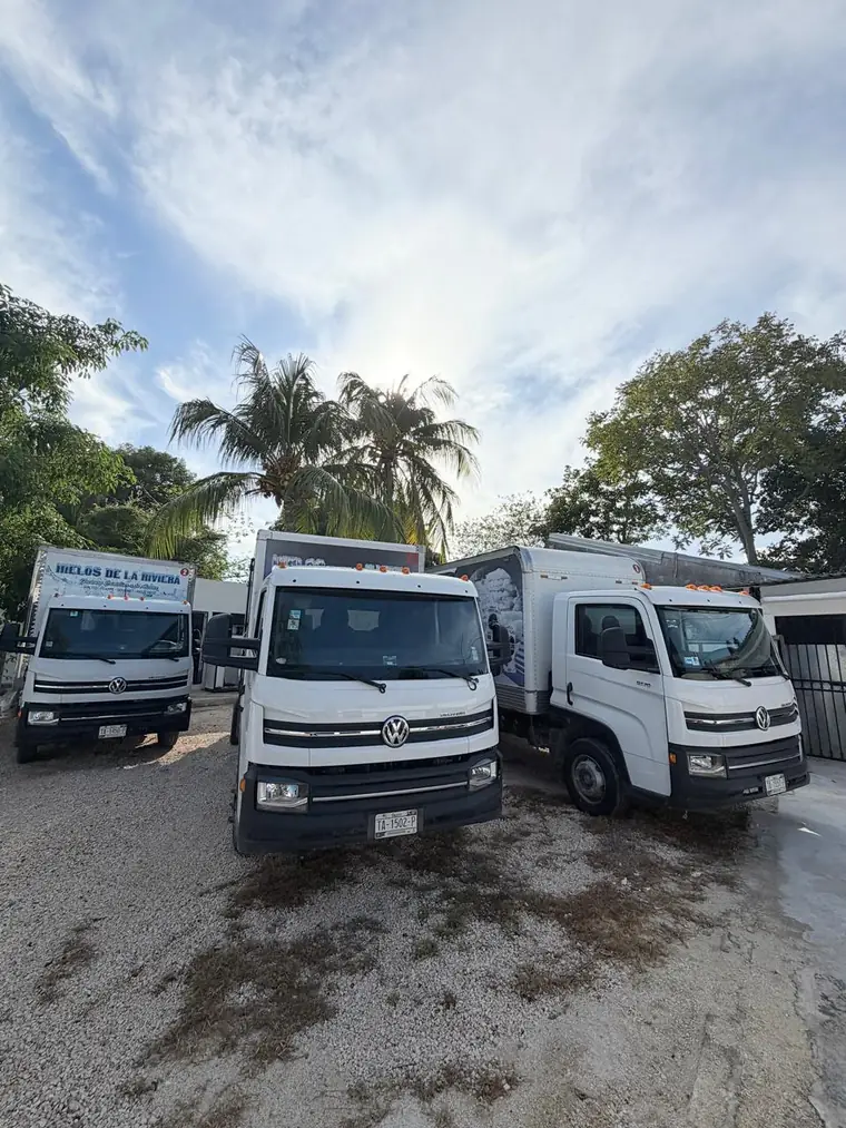 Tres camiones de reparto de Hielos de la Riviera estacionados en el patio.